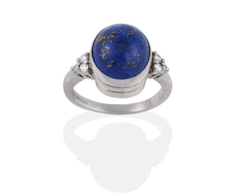 An 18 Carat White Gold Lapis Lazuli and Diamond Ring, the oval cabochon lapis lazuli in a rubbed over setting, to shoulders e