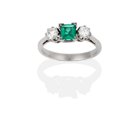 An Emerald and Diamond Three Stone Ring, the square step cut emerald between round brilliant cut diamonds in white claw setti