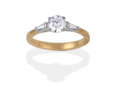 An 18 Carat Gold Diamond Solitaire Ring, a round brilliant cut diamond in a claw setting, to tapered baguette cut diamond sho