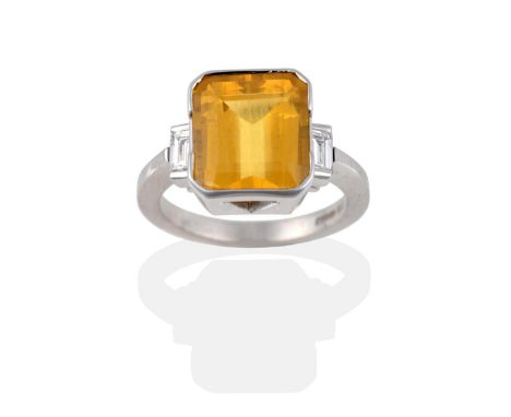 An 18 Carat White Gold Yellow Beryl and Diamond Ring, the emerald-cut beryl in a two part collar setting, above a baguette cu