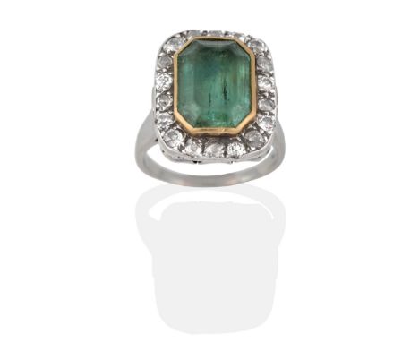 An Emerald and Diamond Ring, an octagonal cut emerald in a closed backed grain setting and within a border of old cut diamond