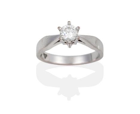 A Diamond Solitaire Ring, a round brilliant cut diamond in a white six claw setting, to pointed shoulders on a plain polished