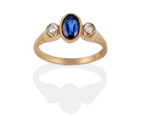 A 9 Carat Gold Sapphire and Diamond Ring, the oval mixed cut sapphire in a rubbed over setting between two round brilliant cu