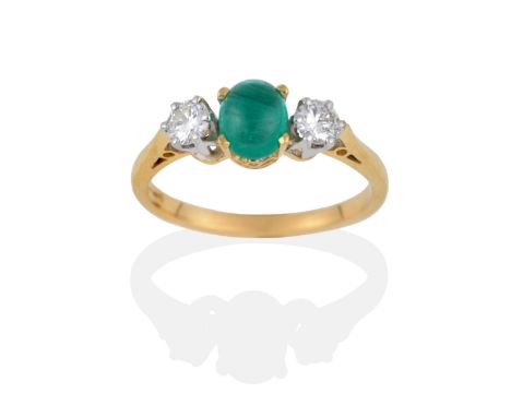 An 18 Carat Gold Emerald and Diamond Three Stone Ring, the oval cabochon emerald in four yellow claws, between two round bril