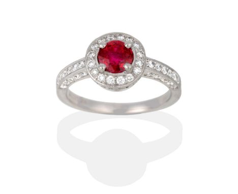 A Platinum Ruby and Diamond Cluster Ring, a round cut ruby in a claw setting, within a circular border of millegrain set roun