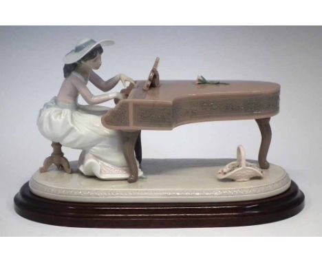 Lladro figure 'Spring Recital', modelled as a lady playing the piano, model 6452, with wood base, 32cm wide     Condition rep