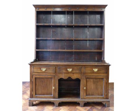 19th century oak dresser, ogee mould above three shelves with an array of cup hooks, pine boarded back, base with three friez