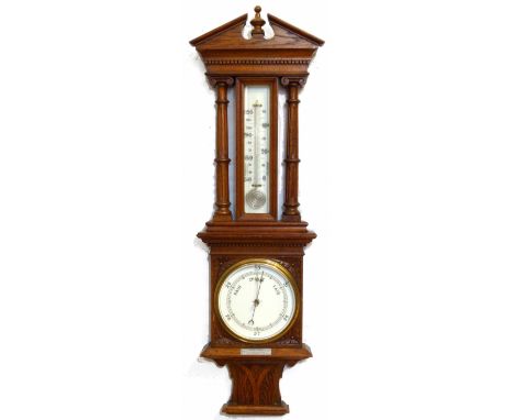 Carved oak aneriod barometer, the architectural pediment on fluted columns, enclosing a thermometer and forecasting barometer