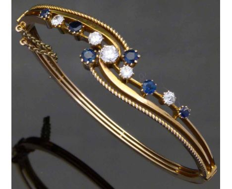 Sapphire and diamond hinged bangle circa 1920, set in ummarked gold, width 55mm inside, gross weight 15.4g. Condition report: