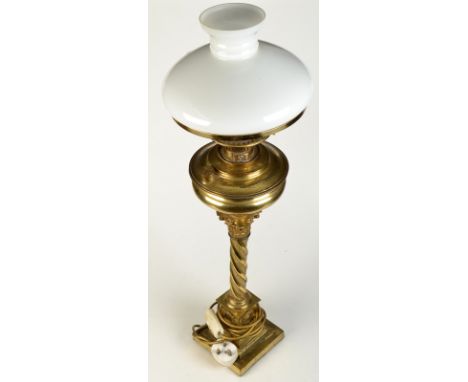 A brass oil lamp on a twist column with a Corinthian capital  and with a white glass shade