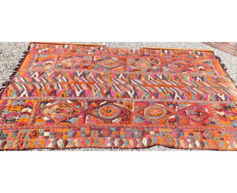 An Iraqi flat weave wall hanging with panels of stylised figures, birds, quadrupeds and other motifs, 160 x 275cm. Condition 