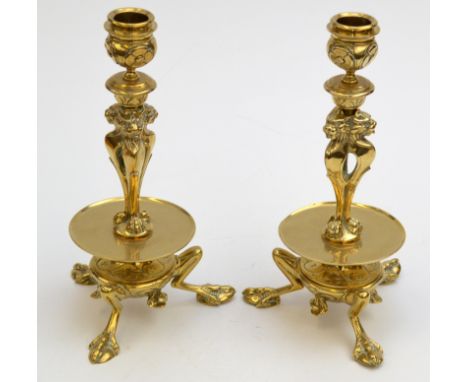 A pair of 19th century brass tripod candlesticks, each cast with lion's masks on claw feet above a drip tray, Height 23.5cm. 