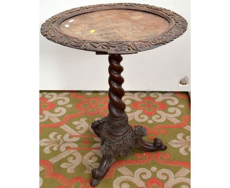 A Victorian occasional table ornately caved to the oval rim and tripod base.