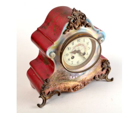 A Louis XV style mantel clock in a ceramic case painted with a landscape and with cast brass finial and feet.  Height 28cm. 