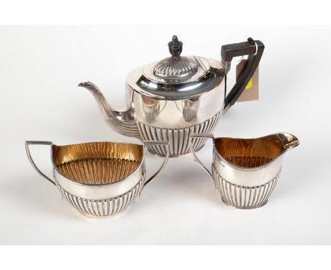 A silver three piece, half fluted tea service of oval form, Sheffield, the teapot and milk jug by Atkin Brothers, 1906, the s