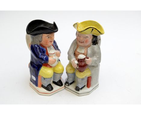 Two late 19th or early 20th century Staffordshire Toby jugs, each seated figure holds a frothing mug and a pipe.
