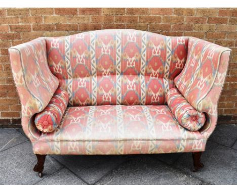 A HIGH BACK UPHOLSTERED SOFA  with shaped arms and bolster cushions, on mahogany supports with ceramic casters, 146cm wide 77