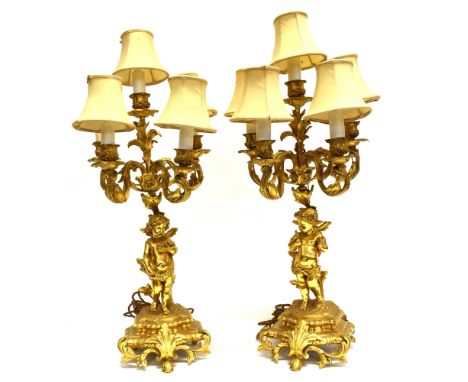 A PAIR OF GILT METAL FIVE LIGHT TABLE LAMPS  with cherub supports, 54cm high excluding electrical fittings