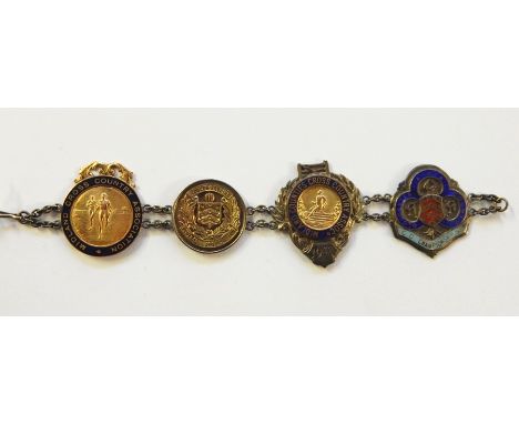 Bracelet having four 1920's and later sporting medallions, to include 9ct gold cross country and three silver and enamel meda