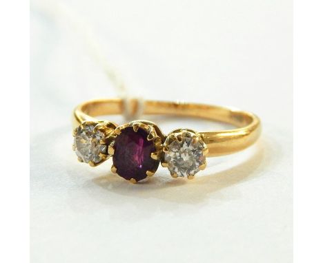 18ct gold, ruby and diamond ring, the central oval ruby flanked by smaller brilliant cut diamonds, in a raised claw setting
