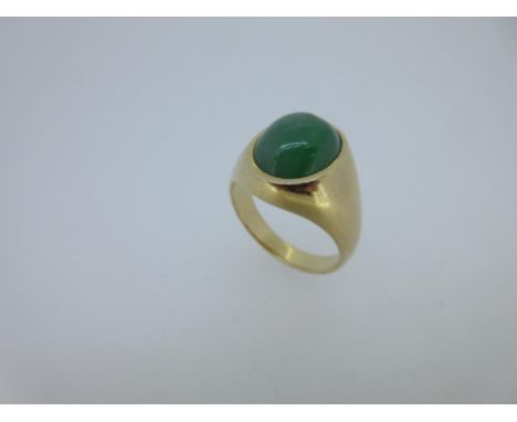 A signet ring set with jade, the oval cabochon slightly mottled mid green jade rubover set in a tapered mount, shoulders and 