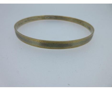 A 9ct bi-colour gold arm bangle, the uniform hoop with white gold central band edged on each side with yellow gold strips, wi