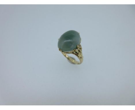 A jadeite jade ring with cast floral shoulders, the oval cabochon jade of mottled sage green, measuring approximately 15 x 12