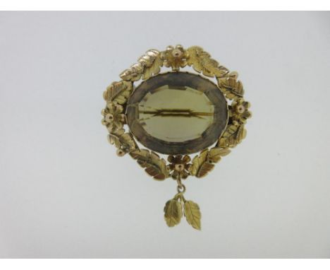 A Victorian smoky citrine brooch with foliate and floral mount, the oval cut light brownish yellow citrine scallop collet set