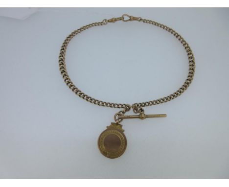 A 9ct gold double albert watch chain and pendant medal, the graduated curb link chain with lobster claw ends, joined by the T