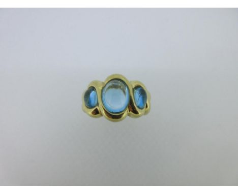 An 18ct gold ring set with three blue hardstones, the graduated oval cabochons of transparent light turquoise blue, rubover s