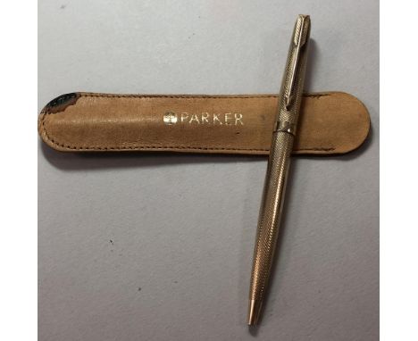 Parker - A 9ct gold retractable ballpoint pen, decorated all over with engine turned engraving around a vacant rectangular ca