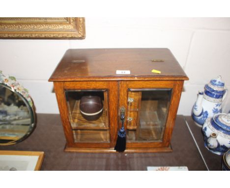 An oak and glazed smokers cabinet containing a Bakelite table lighter AF