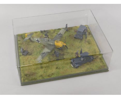 A die cast model of a WWII German Messerschmitt BF109E-3, in a diorama with figures and automobiles, scale 1:48, perspex case