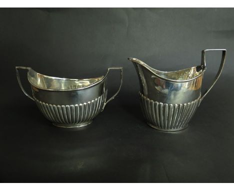 A silver twin handle sucrier together with a milk jug, both with stirrup handles, fluted lower halves, including London 1904,