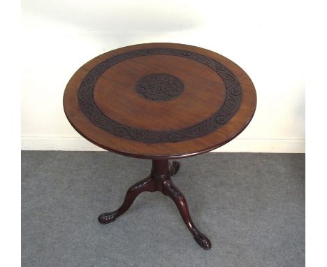 A George III mahogany circular revolving tilt top wine table with carved decoration and bird cage action on turned column and