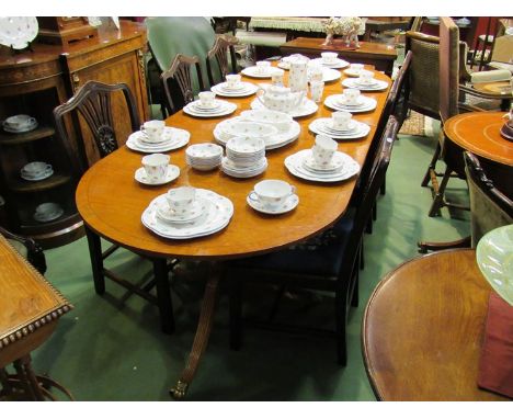 A George III style cross banded satin wood twin pedestal extending dining table with two extra leaves on turned column and tr