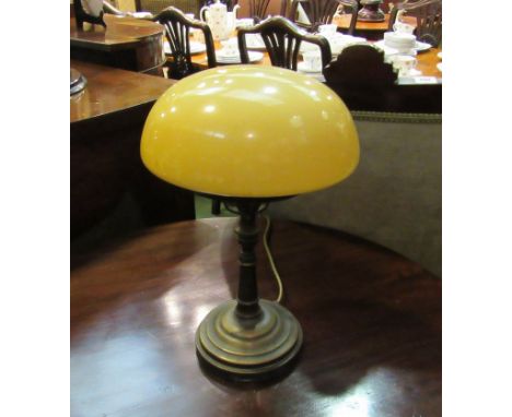 A brass table lamp on circular base with domed opaque glass shade