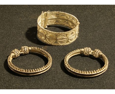 A white metal filigree bangle; another pair of white metal bangles (3) 