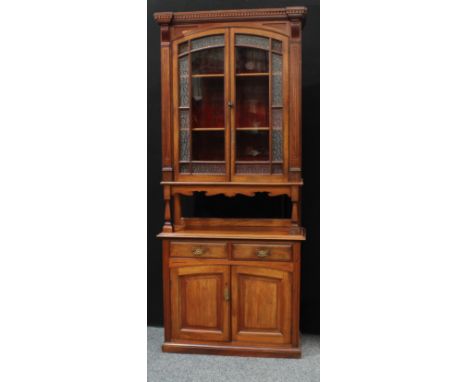 An 'Aesthetic Movement' design bookcase cabinet, dentil cornice above a pair of glazed doors enclosing two shelves, above an 