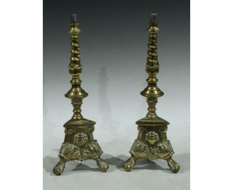 A pair of brass candlesticks, converted for electricity as table lamps, tripod bases, the brass component 33cm 