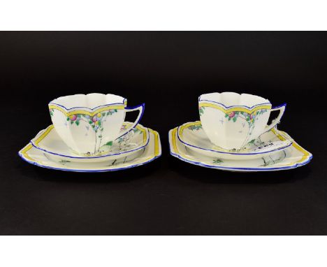 A Pair Of Shelley Art Deco Queen Anne Trios Two in total each comprising charger, saucer and cup, each in yellow, blue, and g