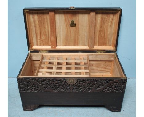 A camphor lined trunk, the top and sides ornately carved with dragons, together with a triangular rush seated chair.