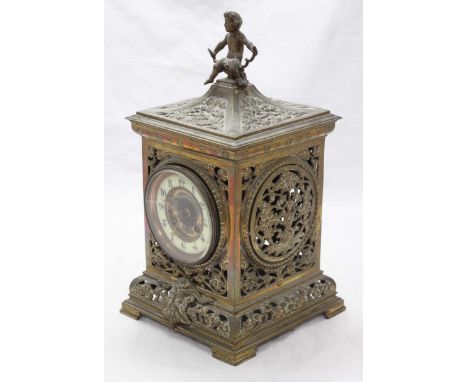 A pierced and heavily ornate brass mantel clock, the white dial with Arabic numerals denoting hours, housed in a case decorat