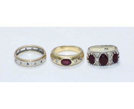 A yellow metal ring, (tests as 18ct), centrally gypsy set with an oval faceted ruby 'coloured' stone flanked by four rbc diam