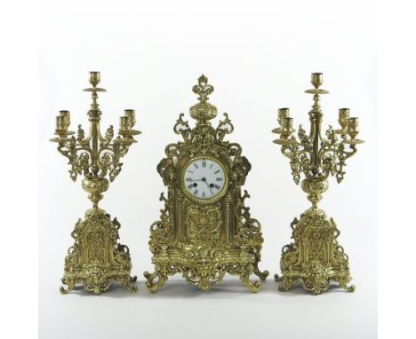 A 19th century French brass clock garniture, the enamel dial showing Roman hours, having an eight day movement, flanked by a 