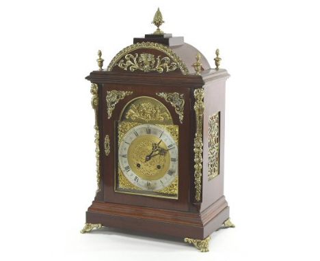 A Regency style mahogany and brass mounted bracket clock, the case surmounted by five pineapple finials, the broken arch dial