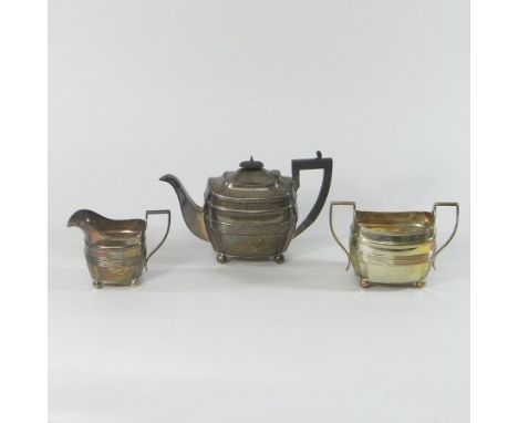 An early 20th century silver three piece tea service, of reeded oval form, on ball feet, comprising a teapot, 26cm long, crea