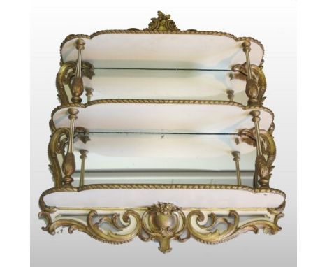 A 19th century gilt decorated and cream painted waterfall wall shelf, with a shaped mirrored back, 93 x 82cm overall