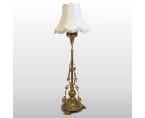 A late Victorian ornate brass standard lamp, decorated with scrolls, with a cream shade, stamped Hinks and Sons to the neck, 