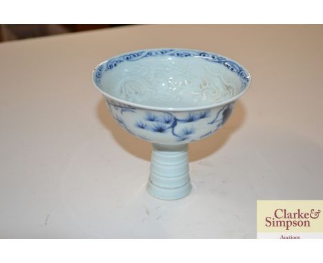 A Oriental blue and white stem cup decorated figures and flowers with dragon relief interior 